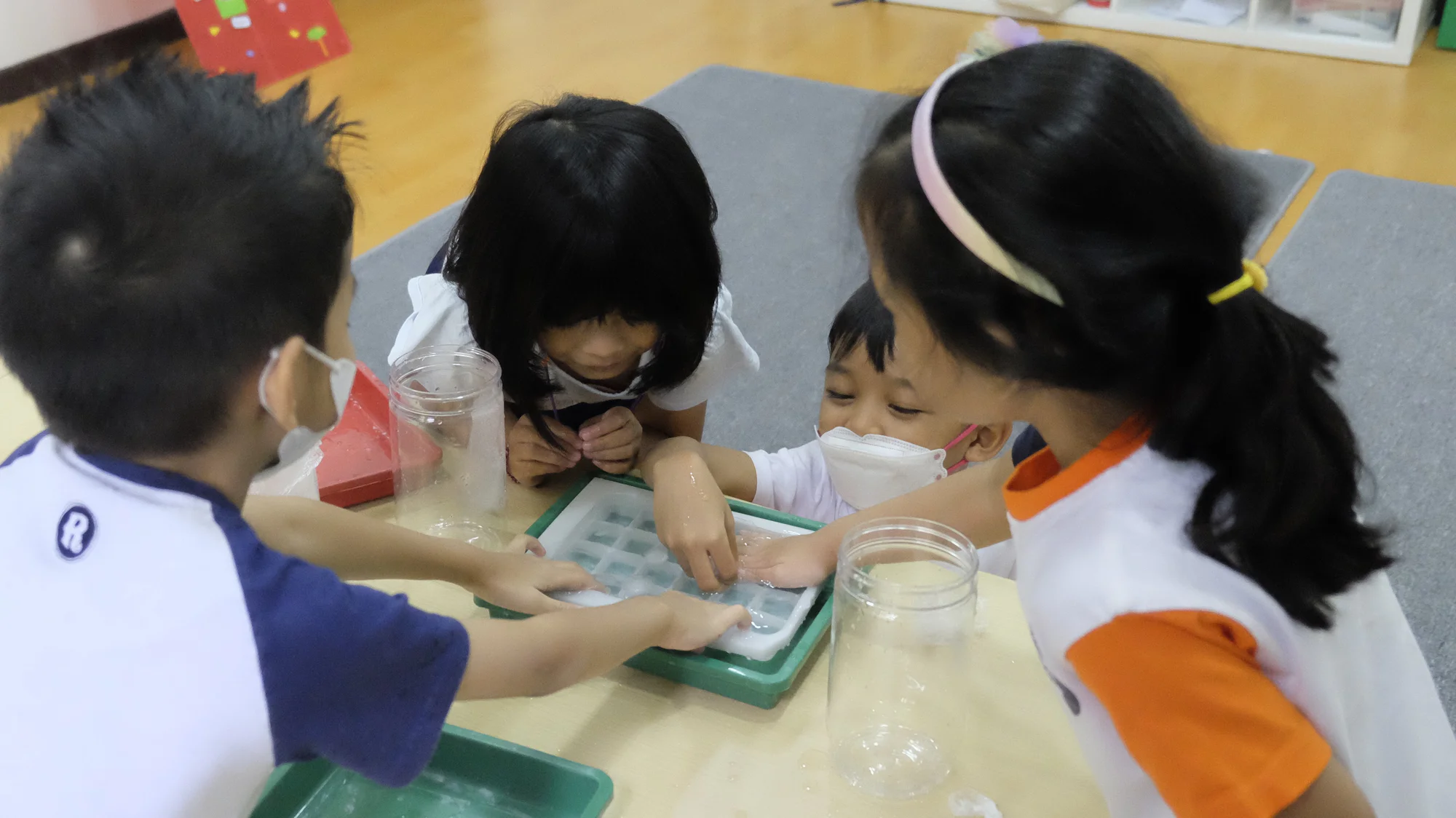 Anak-anak bereksperimen dengan air di meja kelas